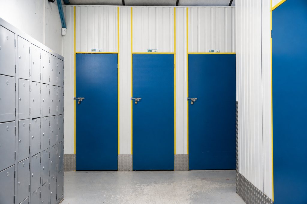 Trois box fermés par des portes bleues à encadrement jaune, dans un couloir du centre